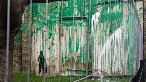 Matt McKenna Banksy's work on a building wall daubed with white streaks of paint