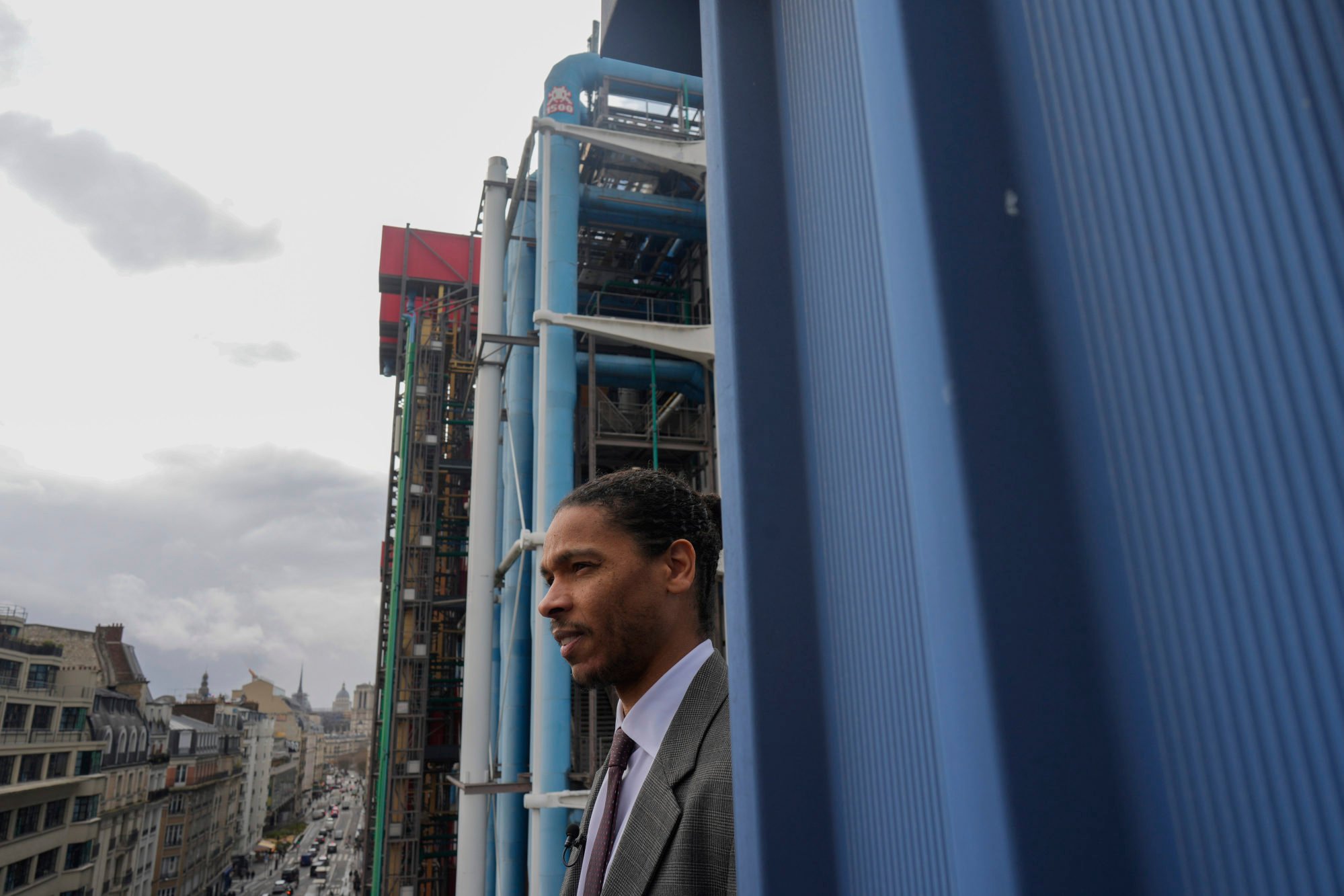 Centre Pompidou director of security Alexandre Aumis stands below the 1,500th mosaic by Invader (on a blue exterior chimney in the background) in Paris. Photo: AP