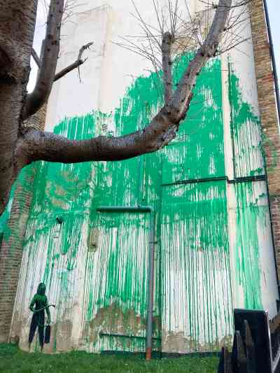 The artwork sits behind a bare tree, giving the impression of leaves