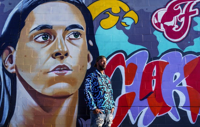Indianapolis street artist Kwazar Martin poses Monday, March 11, 2024, in front of his latest graffiti mural. Kwazar put his focus on Caitlin Clark, Iowa Hawkeyes basketball phenom and community favorite for the Indiana Fever's upcoming No. 1 WNBA draft pick.