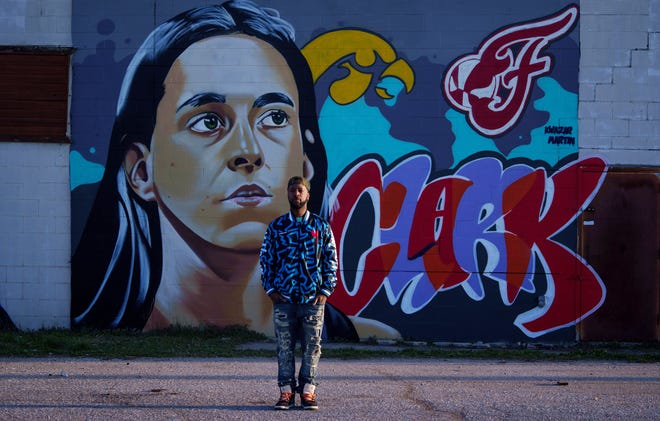 Indianapolis street artist Kwazar Martin poses Monday, March 11, 2024, in front of his latest graffiti mural. Kwazar put his focus on Caitlin Clark, Iowa Hawkeyes basketball phenom and community favorite for the Indiana Fever's upcoming No. 1 WNBA draft pick.
