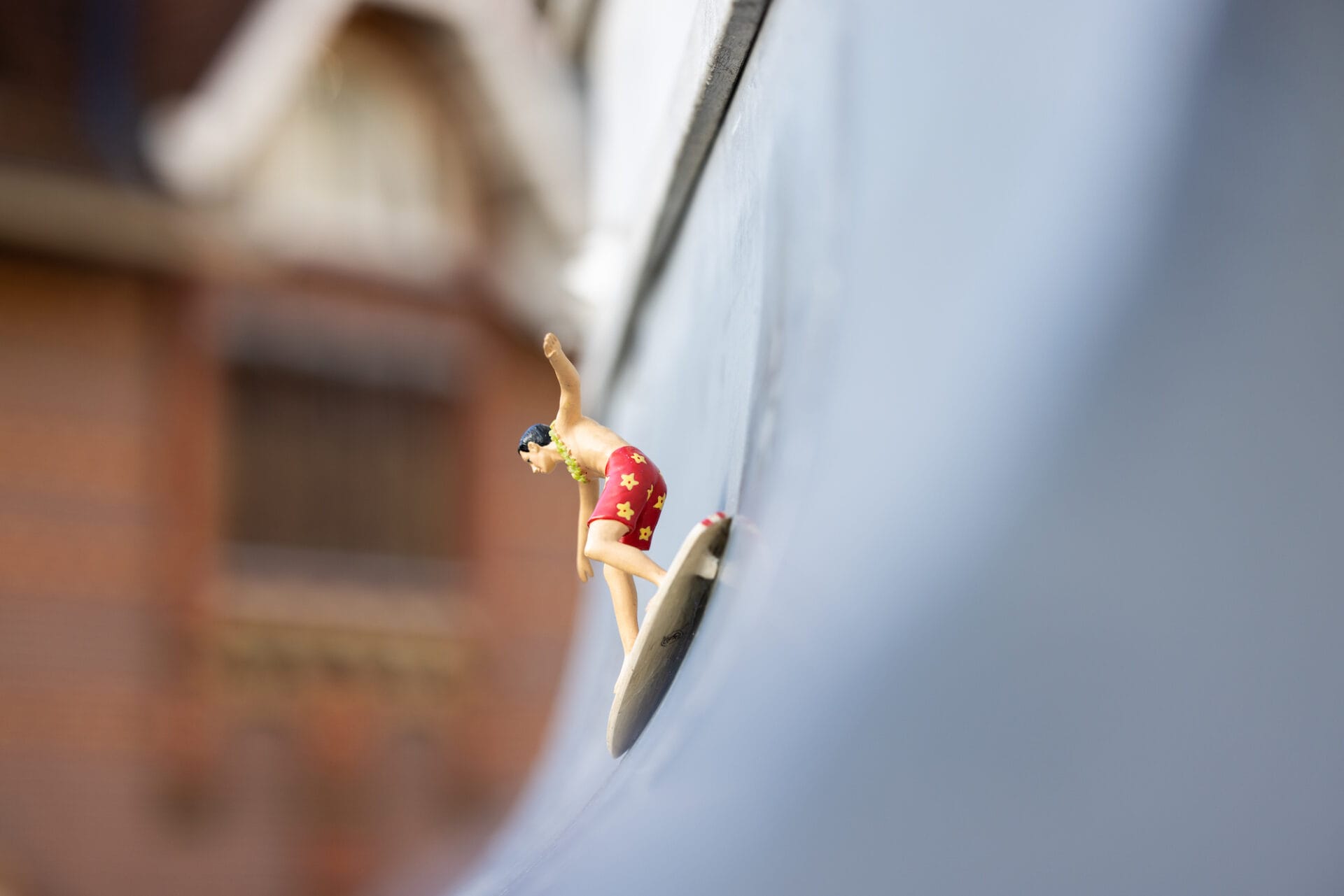 A small sculpture of a surfer sails down an exterior awning