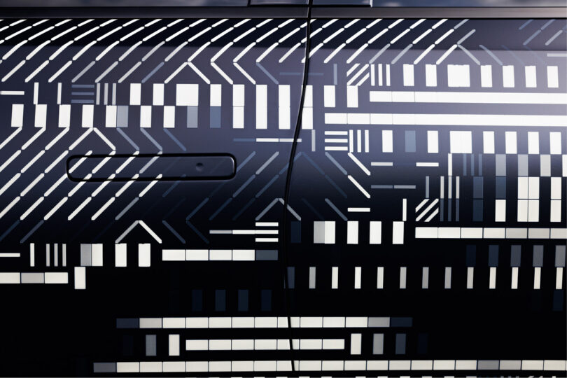 Side driver's side door section of the new Infiniti GX80 wrapped in a monochromatic dash and square pattern designed by digital artist Kaoru Tanaka