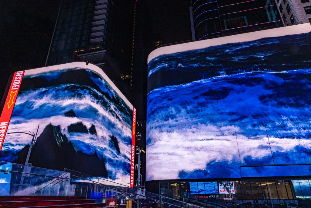 Multiple video screens show images of storms in the center of times square in manhattan
