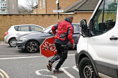 A person removes a piece of art work by Banksy, which shows what looks like three drones on a traffic stop sign, which was unveiled at the intersection of Southampton Way and Commercial Way in Peckham, south east London, Friday Dec.  22, 2023.  (Aaron Chown / PA via AP)