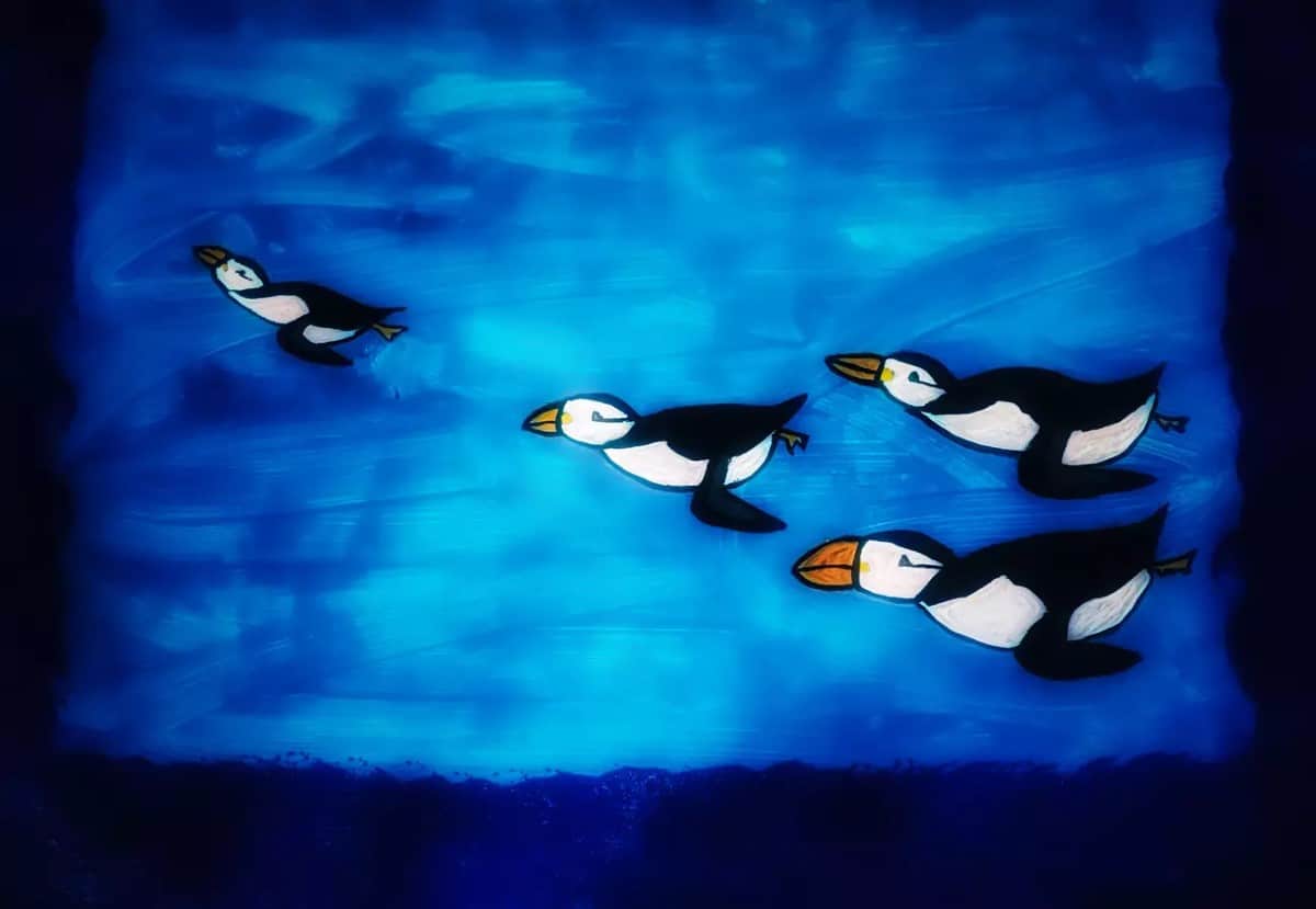Six year old's painting of penguins swimming underwater