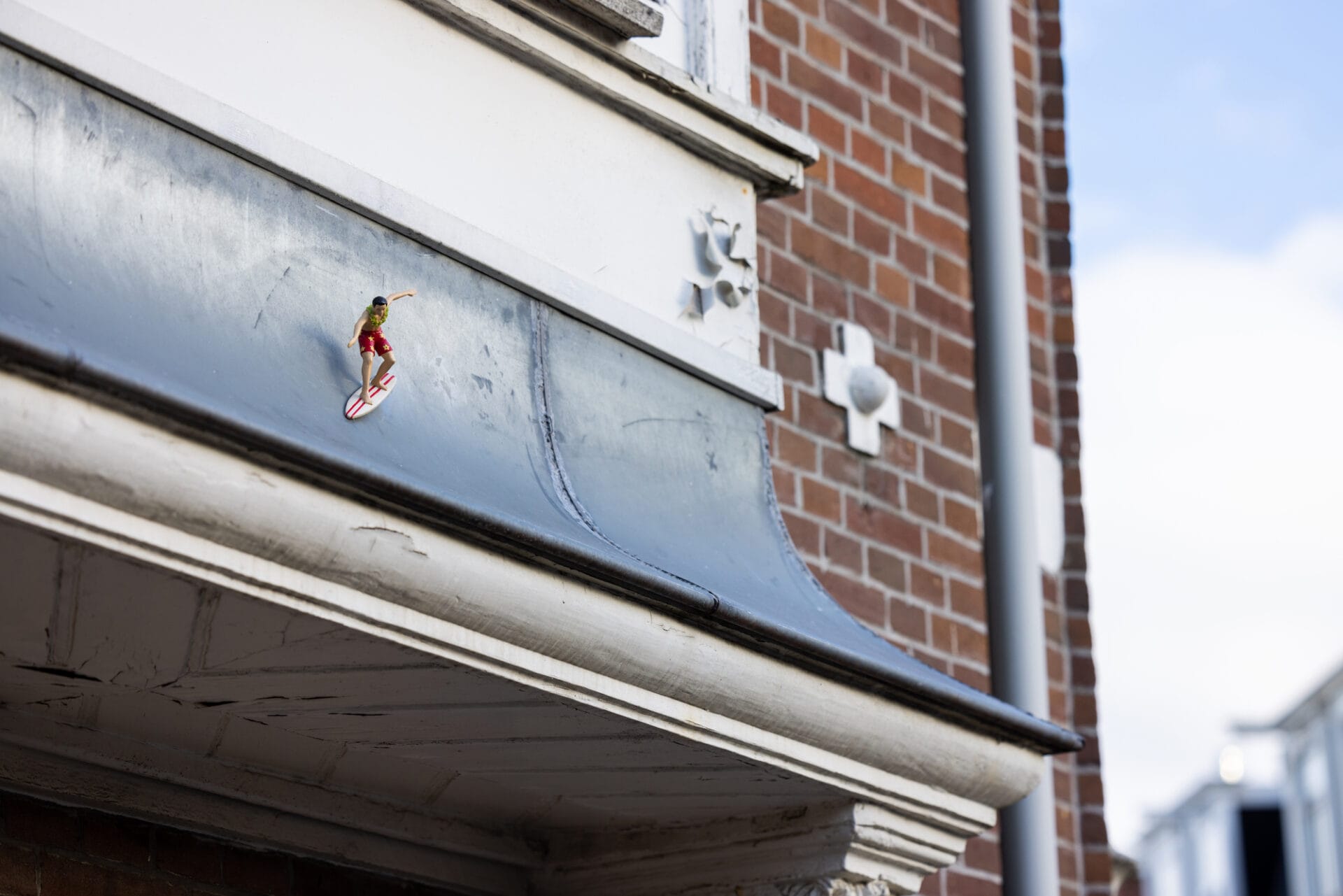 A small sculpture of a surfer sits on the top of an awning