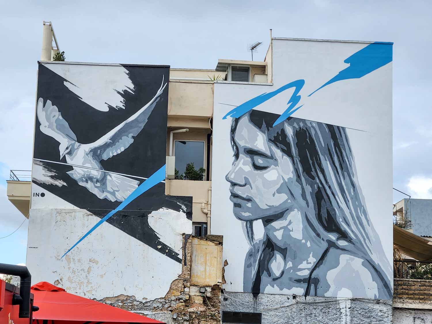 Street art by INO of a woman and a dove in Athens - one of the many pieces to see on a street art tour of Athens with kids