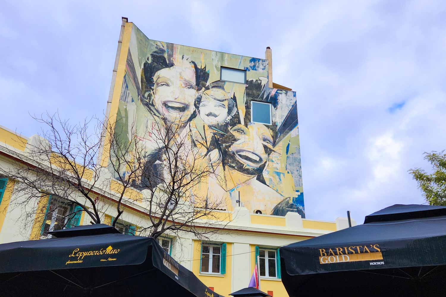 View of a piece of street art in Psiri in Athens using mirrors as well as smiling female faces and yellow sections - the final stop on a street art tour of Athens with kids