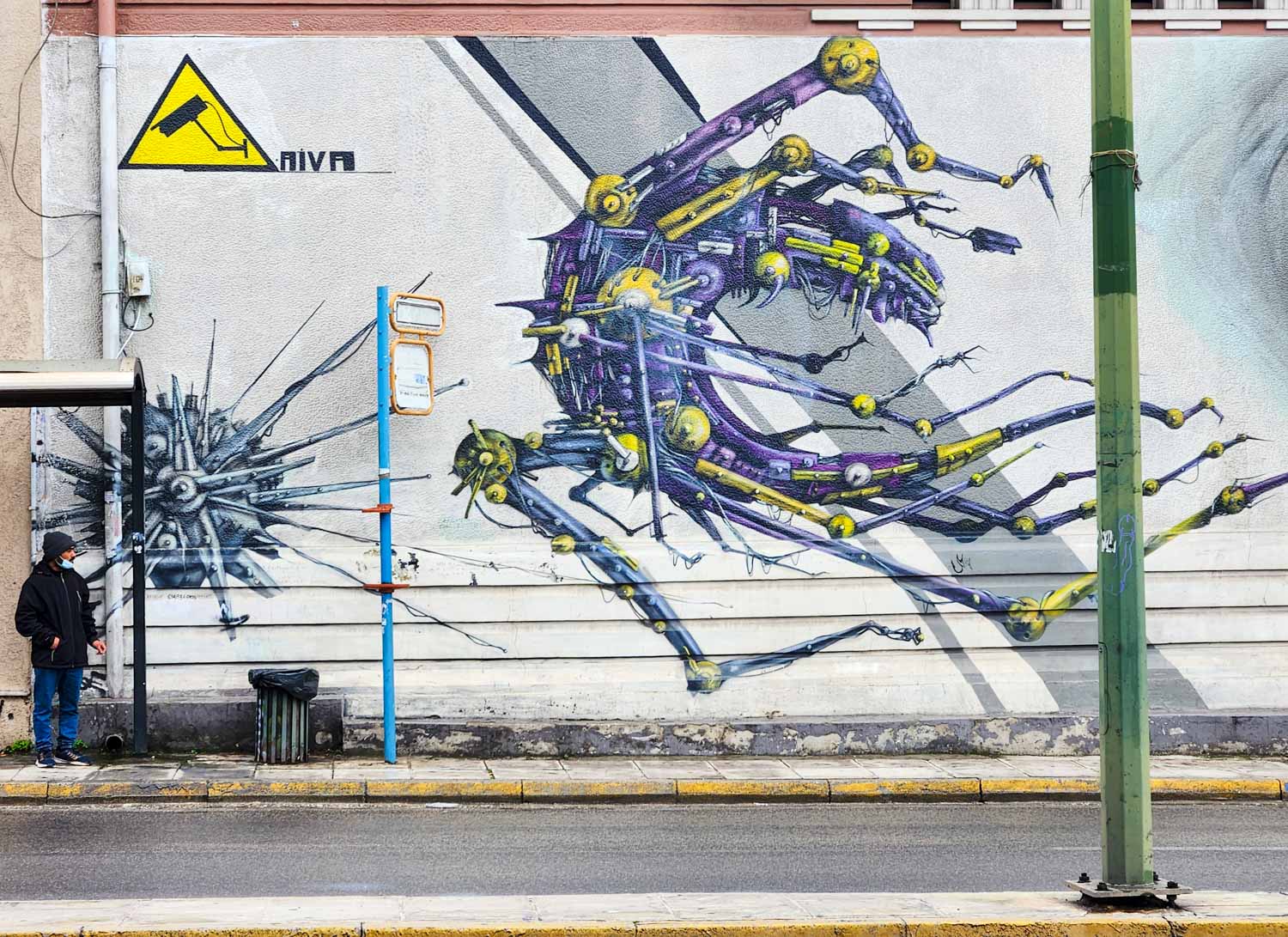 Street art on the side of a building by a bus stop in Athens inspired by technology and computer viruses, looking like a cross between a creature and a machine - my street art tour of Athens review
