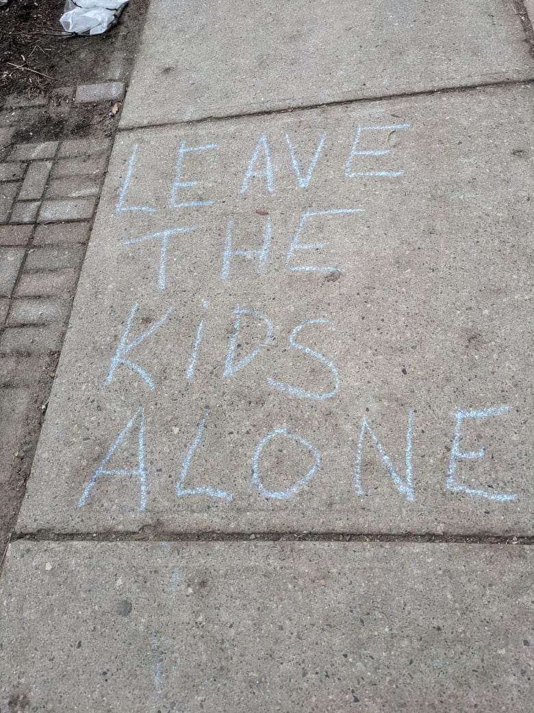 Phrase written in blue chalk on a sidewalk.