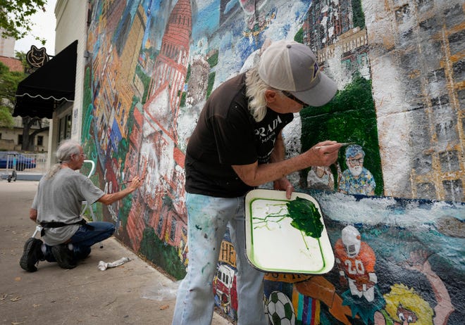 Tom Bauman, left, and Kerry Awn, restore their “Austintatious” mural they originally painted as University of Texas art students in 1973, on the north wall of the University Co-Op Monday April 1, 2024.