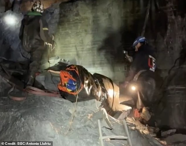 Volunteers carry a dinghy out of the cave after it was left behind by visitors