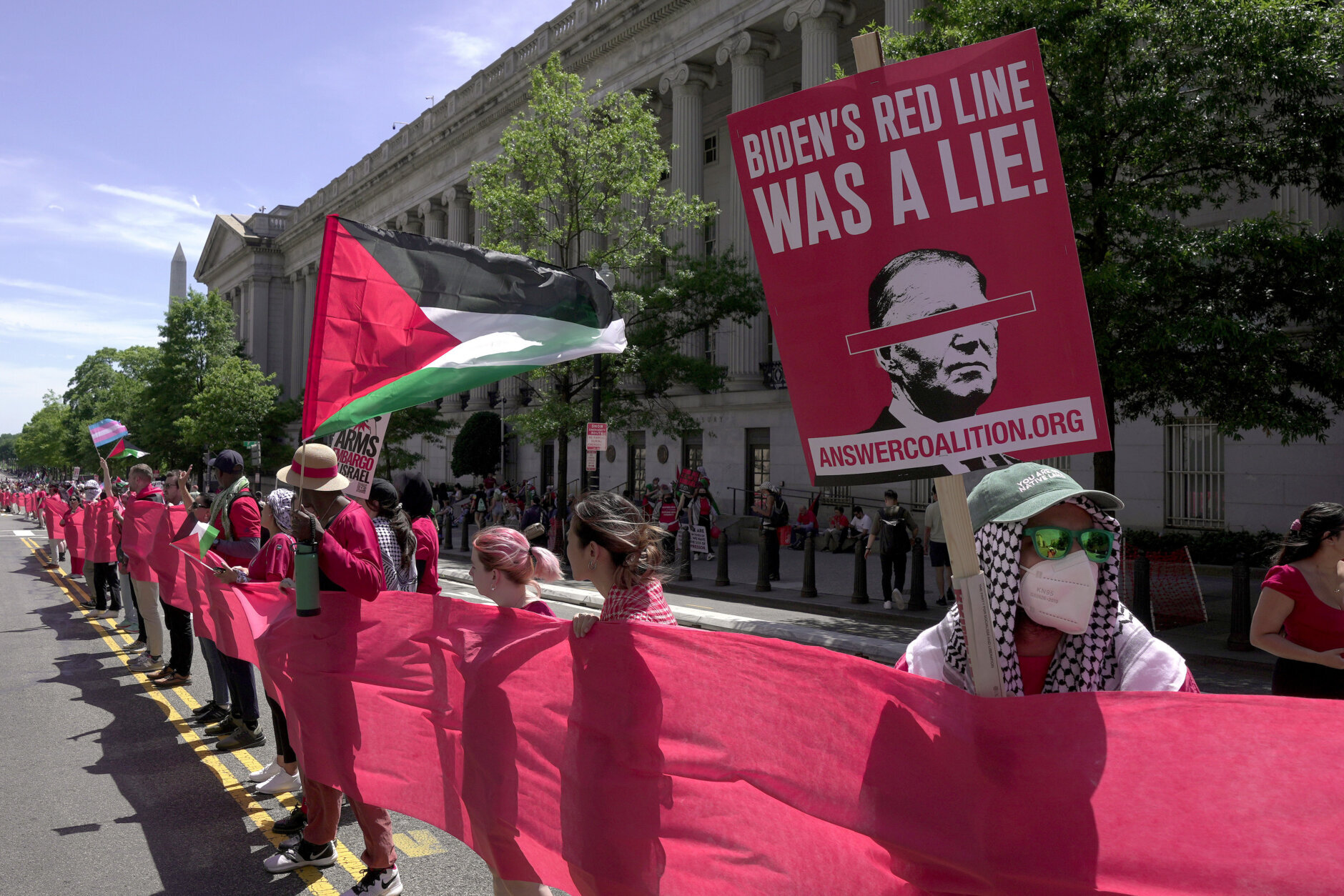 Pro-Palestinian protesters carry a red banner representing a